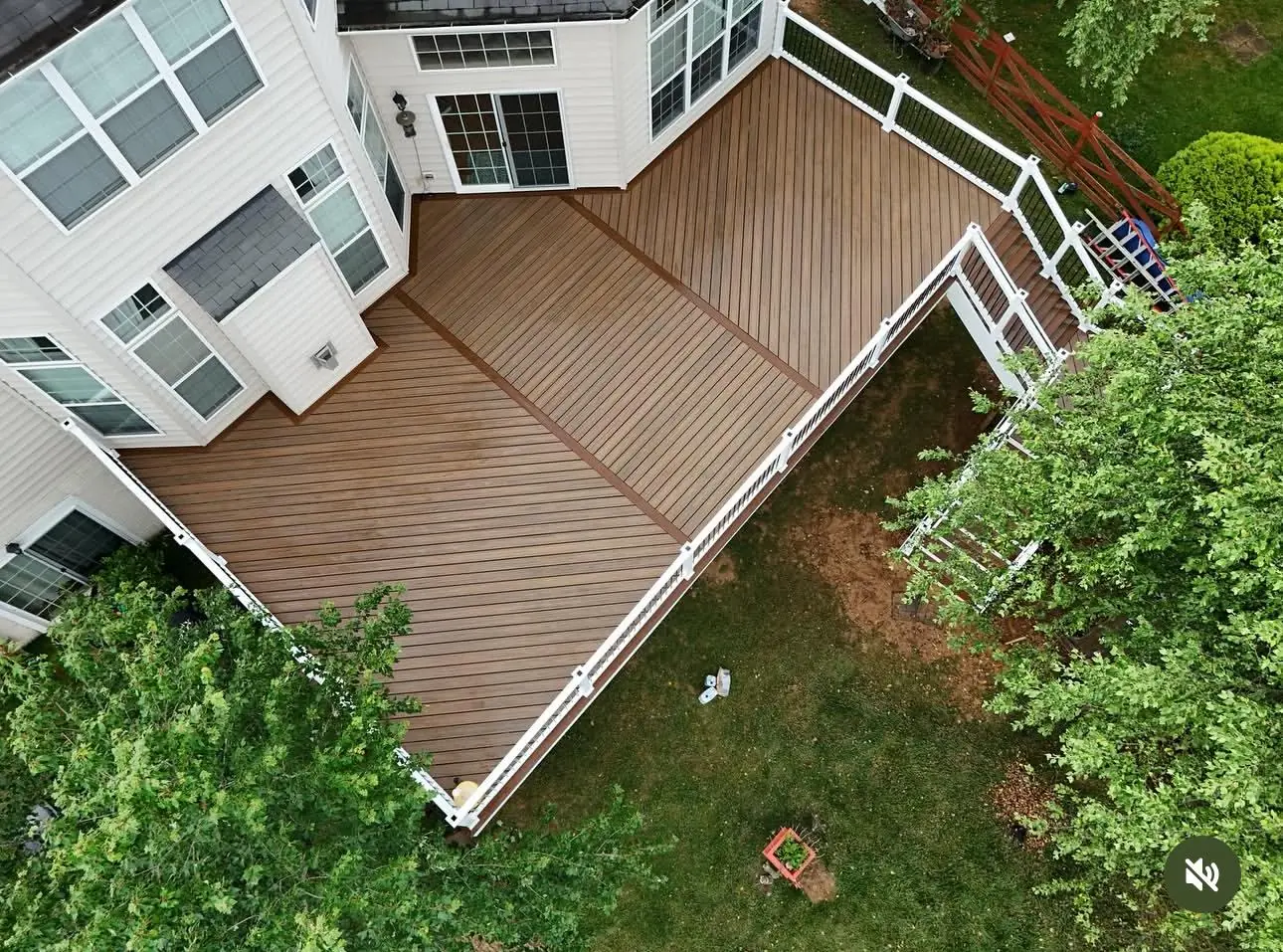 Aerial view of large L-shaped composite deck with white railings surrounded by trees